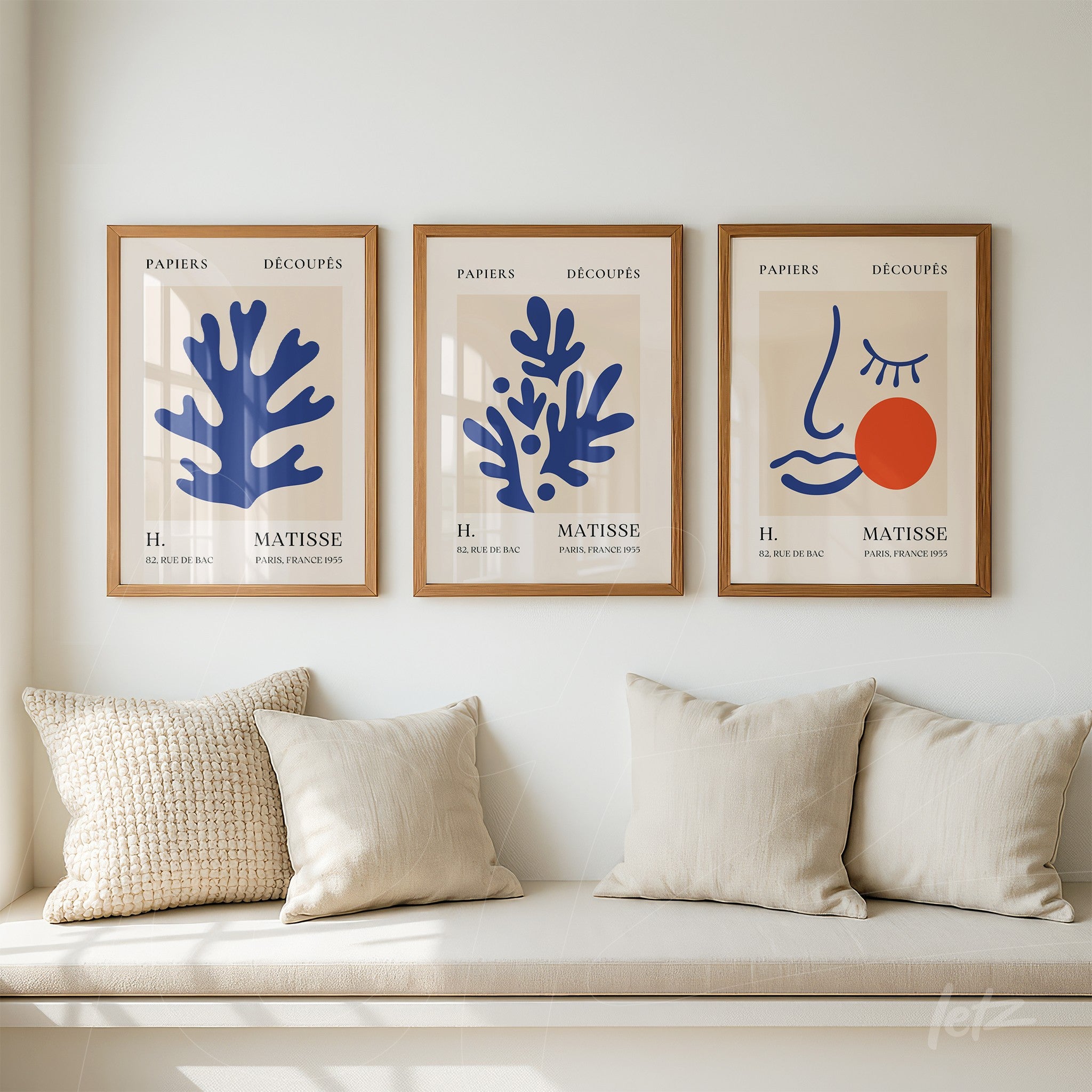 set of three framed artworks showcasing abstract organic shapes in blue and red on neutral background with light wood frames