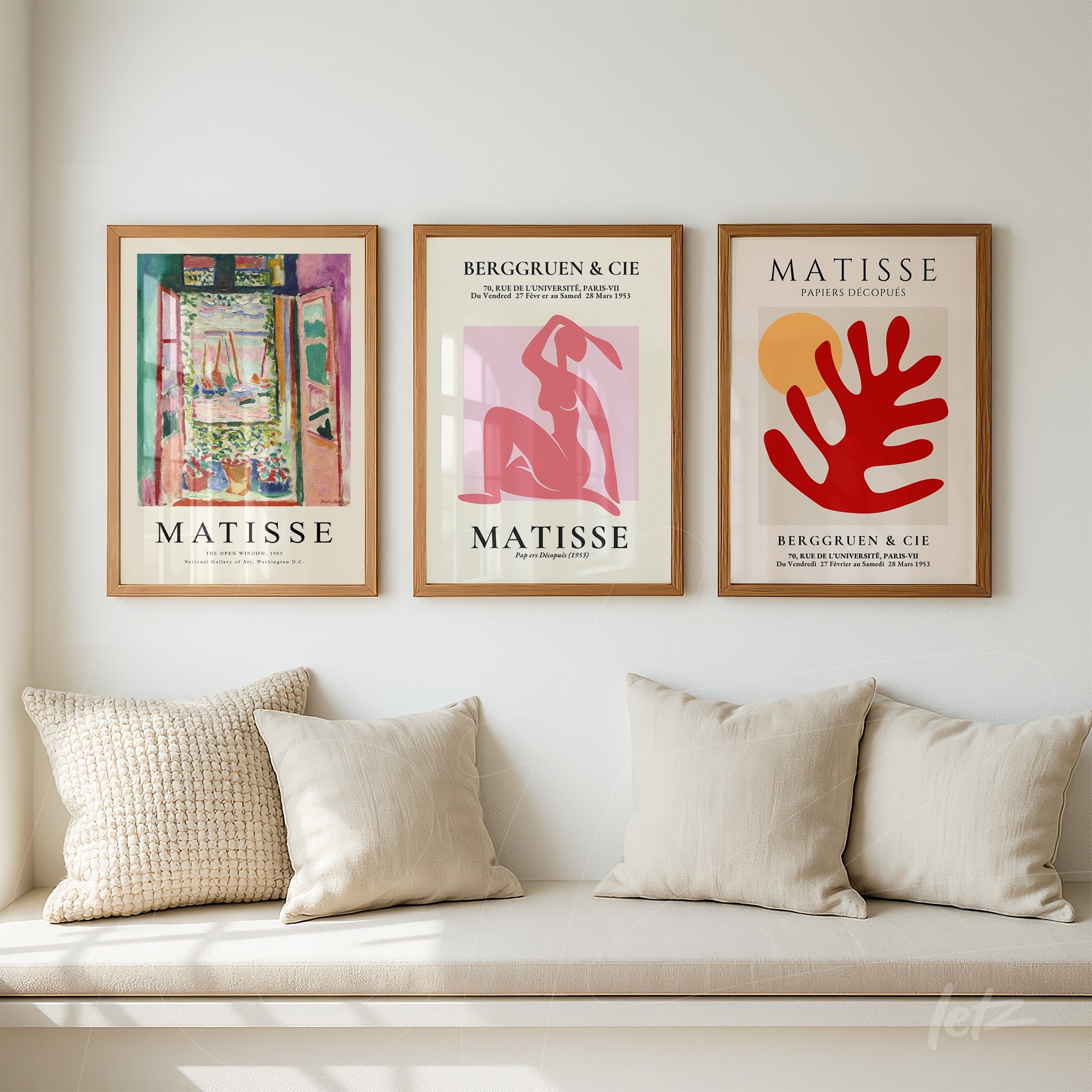 series of decorative framed artworks by Matisse in light wood frames displayed above a sofa with light cushions