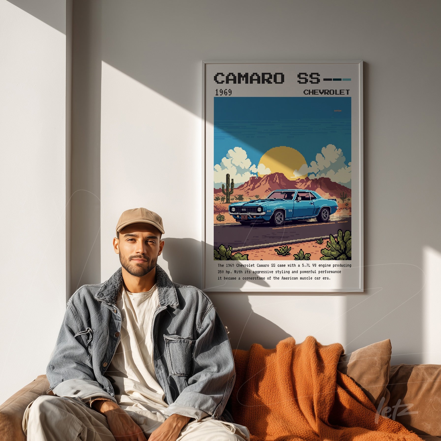 framed retro artwork of 1969 Camaro SS above a man sitting on a sofa with an orange blanket