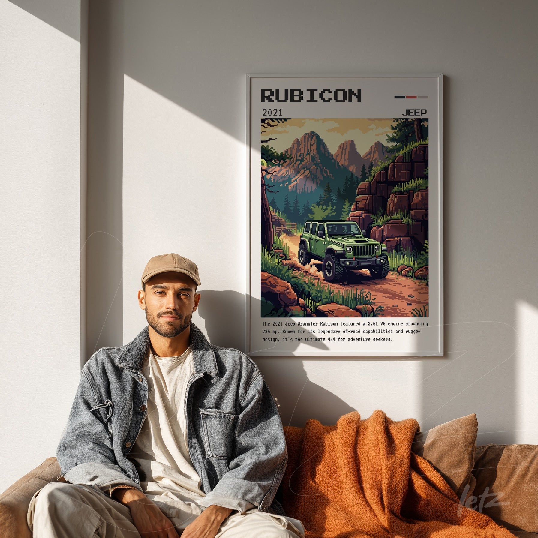 framed retro art print of the Jeep Rubicon in a mountainous background displayed on a light wall with a person sitting beside it