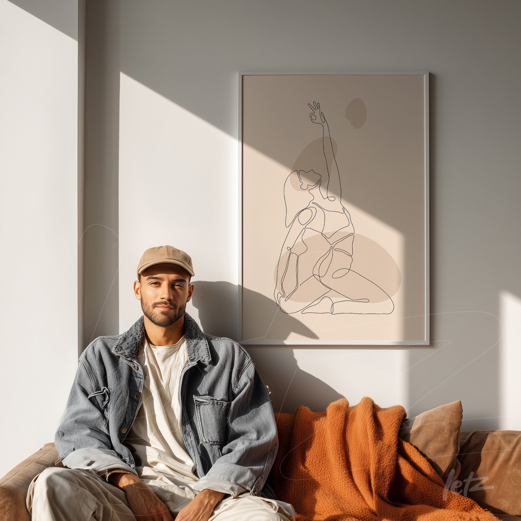 minimalist line art depicting a seated human figure, framed on a white wall behind a sofa with a man and orange blanket