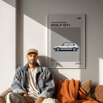 framed wall art featuring a digital illustration of a Volkswagen Golf GTI in gray and blue tones displayed on a light wall beside a man sitting on a couch
