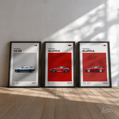 set of framed artworks featuring illustrations of Toyota cars, including AE 86 from 1987, Supra from 2019, and Supra from 1994, displayed on a light wall