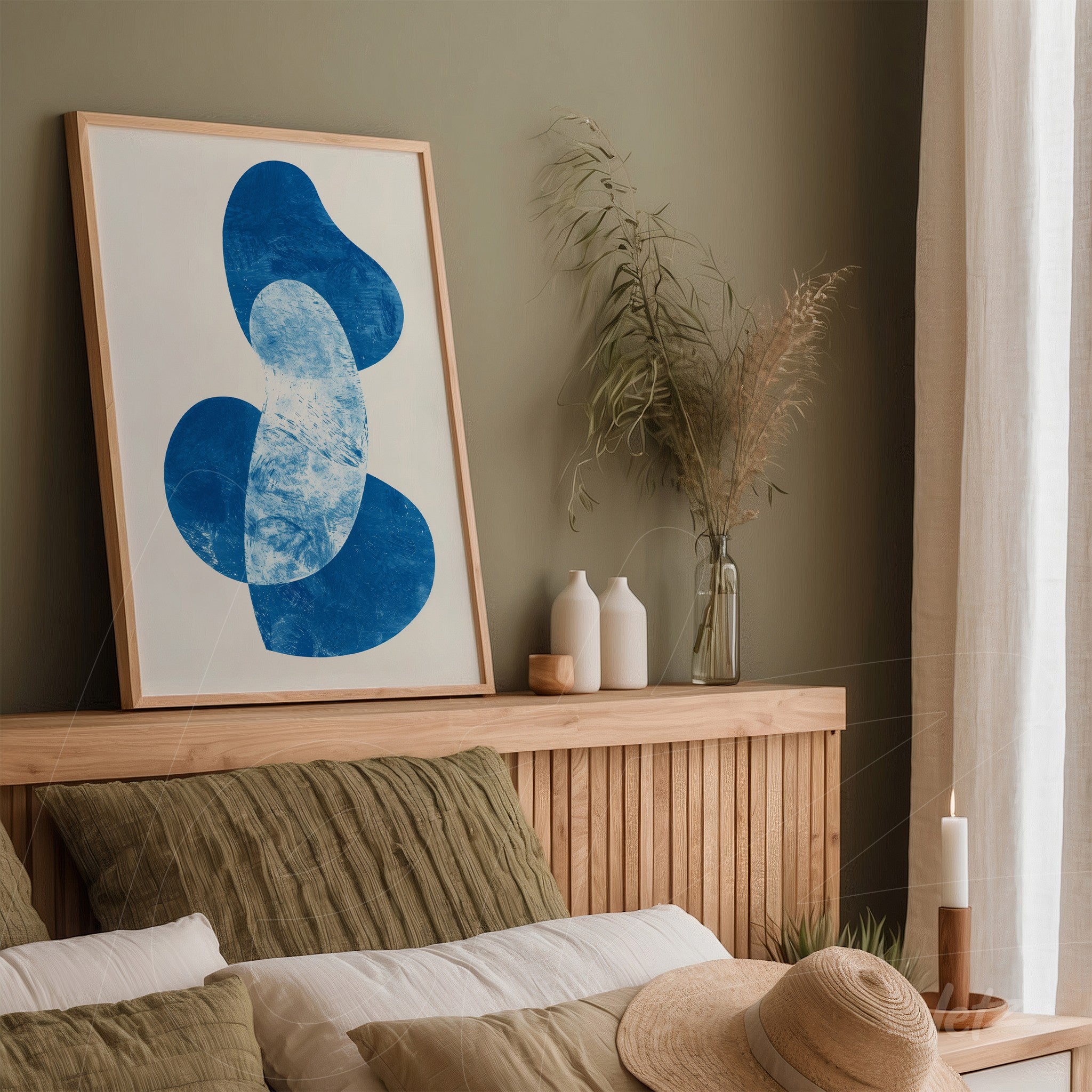 abstract wall art with blue shapes on light background in a light wood frame displayed in a minimalist setting with green wall and natural elements like vases and plants