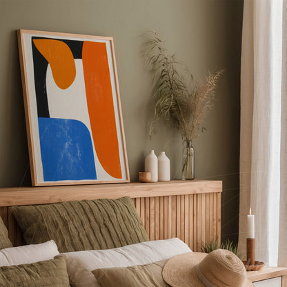 abstract art piece in blue and orange tones in a light wood frame displayed on a wooden headboard with earthy toned pillows