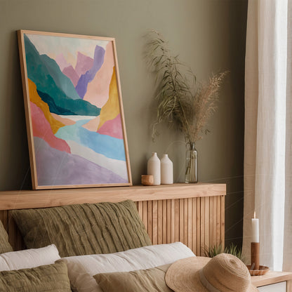 abstract artwork in soft shades of pink, blue, and yellow in a light wood frame displayed on a shelf beside decorative vases and plants