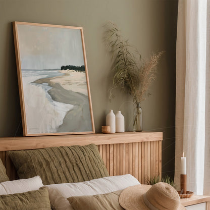 framed artwork depicting a serene beach scene with gentle waves in a light wood frame displayed above a wooden bed headboard with neutral toned bedding
