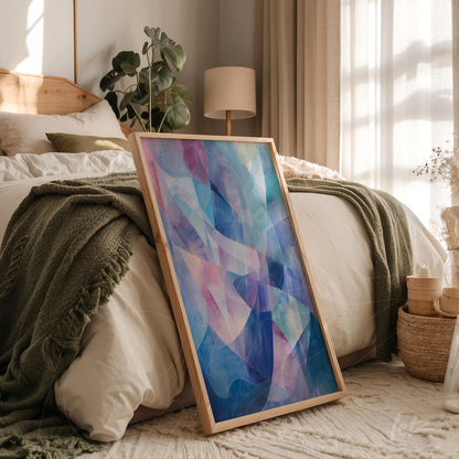 framed abstract art in shades of blue and pink leaning against a bed with green bedding and wooden accents