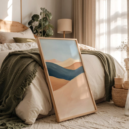 framed abstract art piece in shades of blue and beige displayed in a softly decorated bedroom with a bed and cozy accents