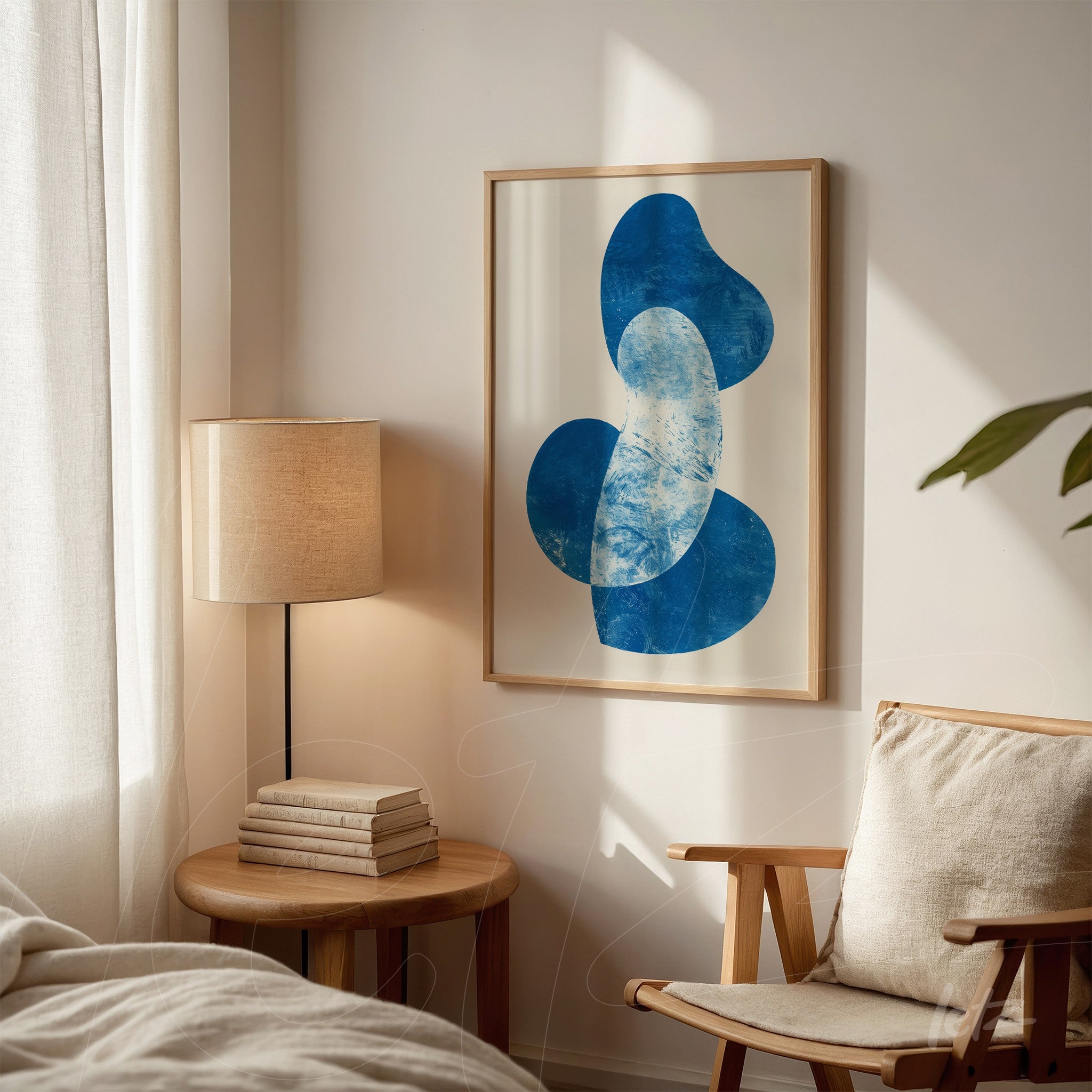 abstract wall art in shades of blue framed in light wood displayed against a light wall next to a lamp and wooden side table