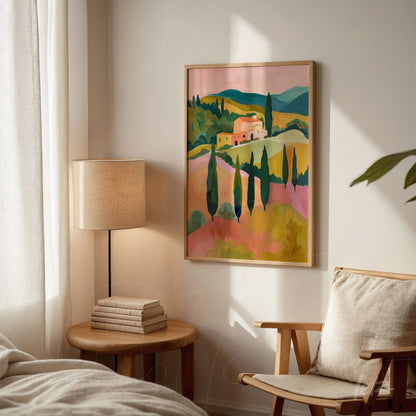 framed wall art featuring a pastel landscape of hills and villas against a light wall next to a floor lamp