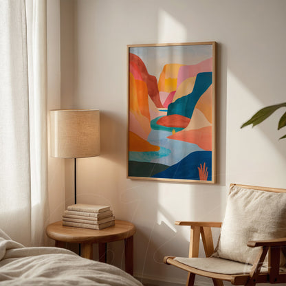 colorful abstract artwork of mountains and a lake in light wood frame displayed in a cozy setting with a wooden table and chair