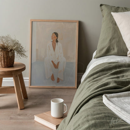 minimalist wall art featuring a seated woman in white clothing with a light frame displayed next to a bed dressed in green bedding and neutral pillows