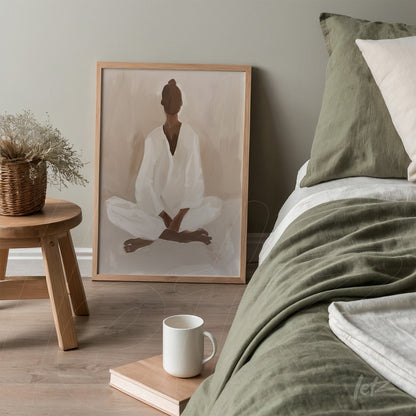 framed minimalist artwork of a meditating figure in light wood frame on a bed with green bedding