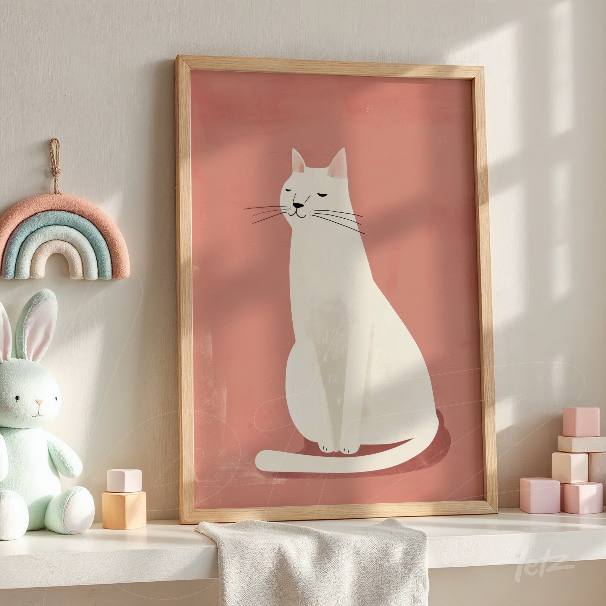 framed artwork of a white cat on a pink background with light wood frame displayed on a shelf with children's toys