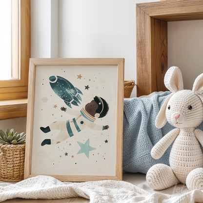 framed artwork with an illustration of a Black astronaut floating in space surrounded by stars and a rocket, displayed in a cozy setting with plush decor