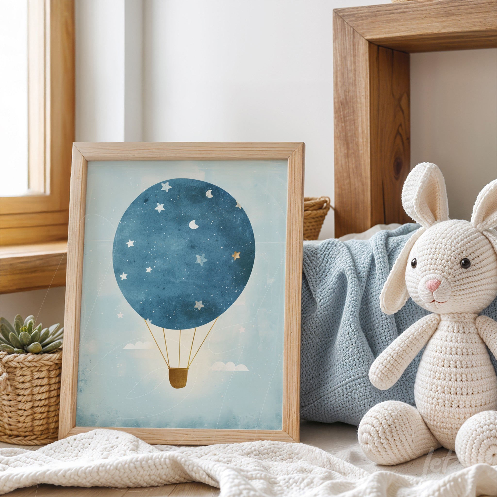 framed artwork of a blue hot air balloon against a light background, light wooden frame, displayed on a shelf next to a plush rabbit