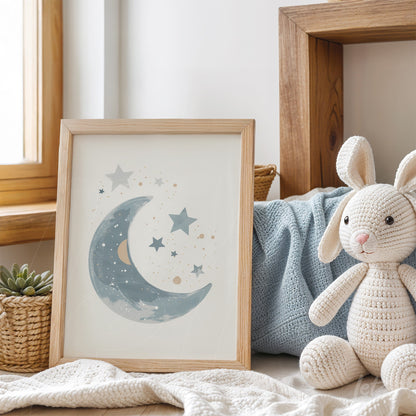 framed artwork of crescent moon in shades of blue featuring stars with a light wood frame, placed on a sofa with a blanket and a stuffed bunny