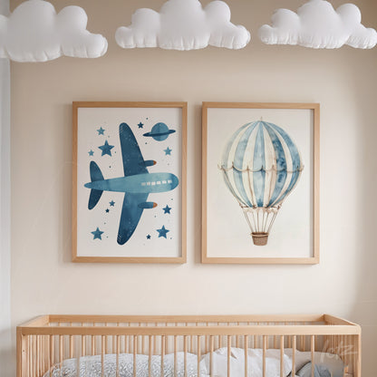 decorative wall art composition featuring illustrations of a blue airplane and a hot air balloon in light wood frames, displayed above a crib in a children's room