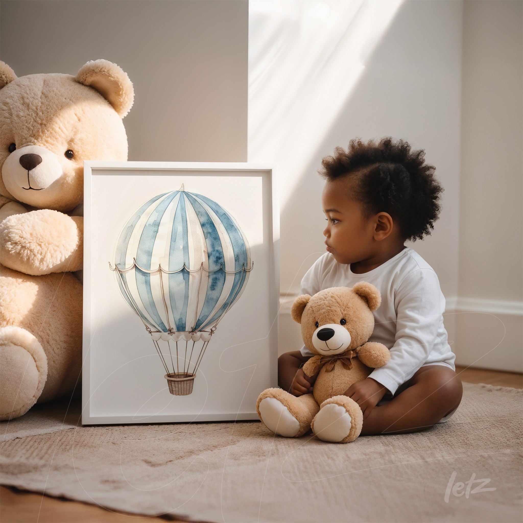 framed art featuring a hot air balloon illustration in a white frame, displayed next to a sitting child holding a teddy bear