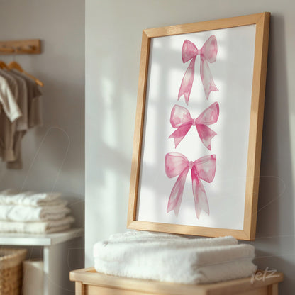 framed artwork featuring pink bows in light wooden frame displayed on shelf with white towels