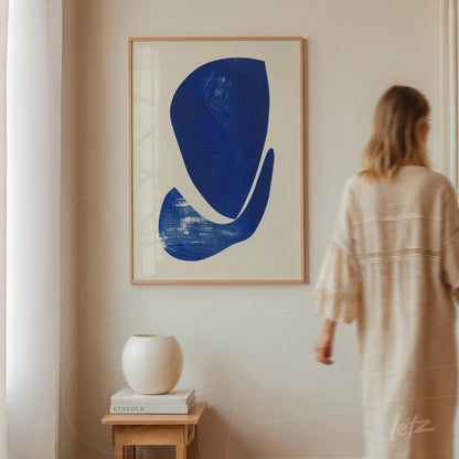 framed wall art featuring abstract blue shapes on white background displayed in a minimalist interior