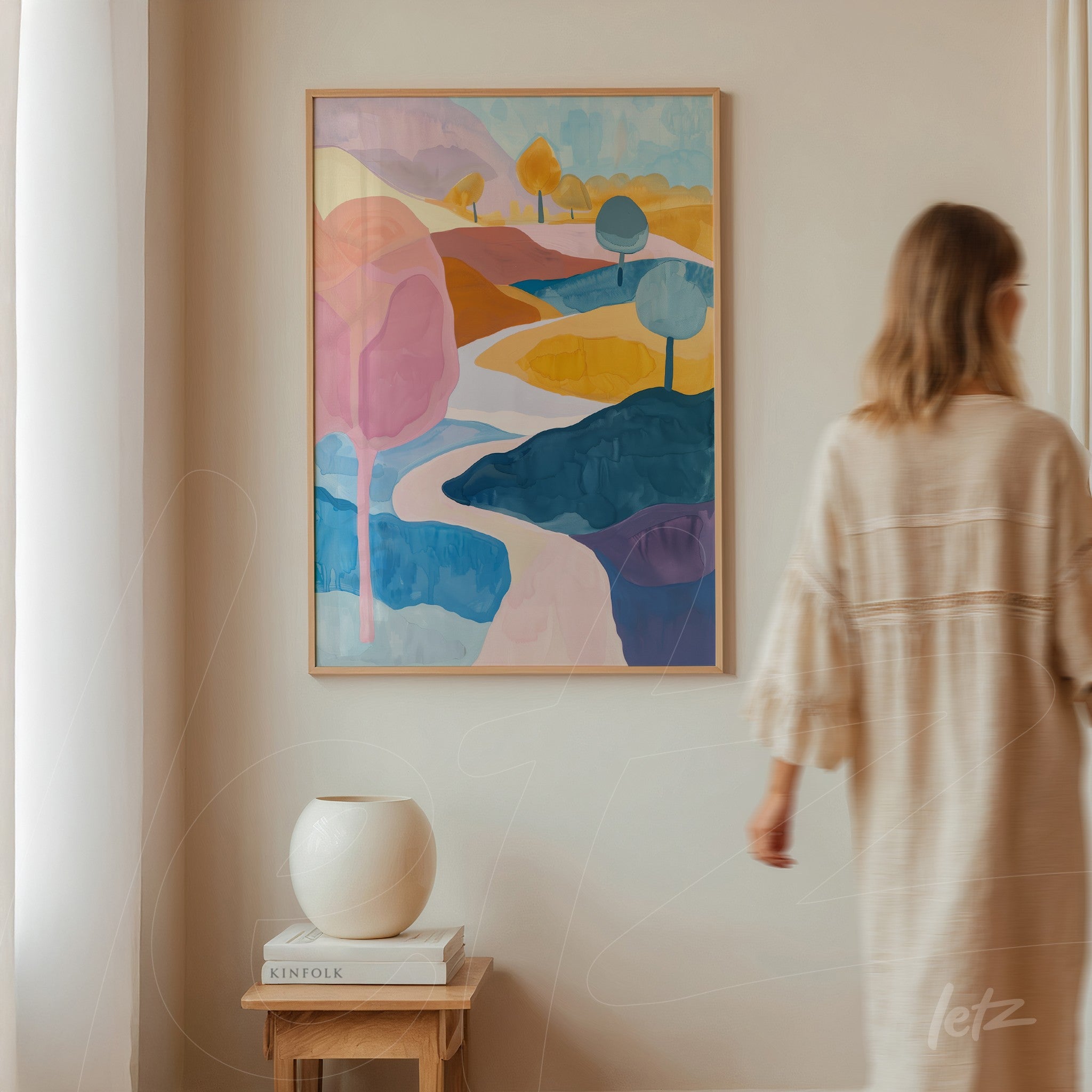 framed abstract landscape art in pastel tones featuring colorful trees and a winding river displayed on a light wall