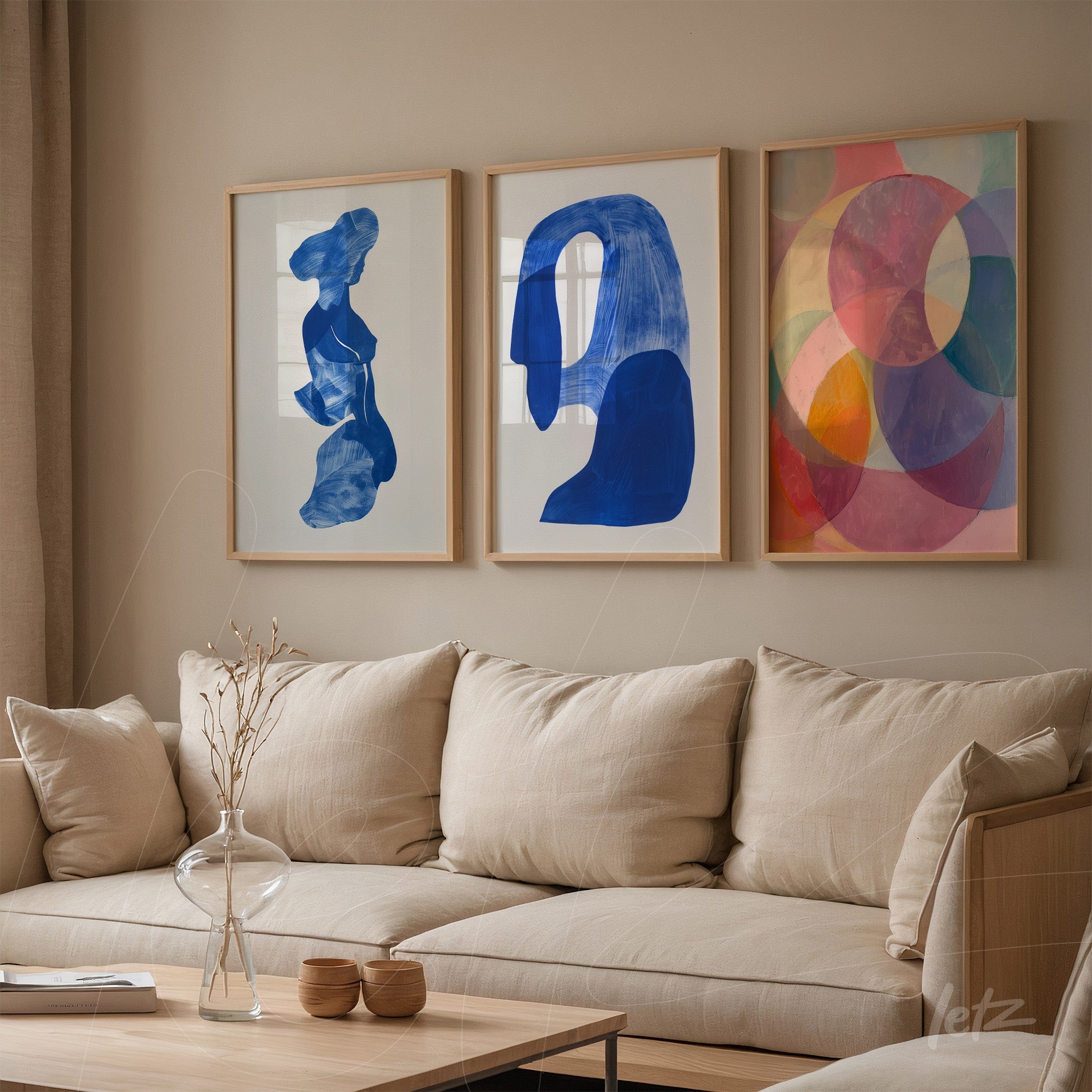 set of three artworks featuring abstract forms in light frames on a neutral wall, showcasing deep blue, silhouette figure, and colorful circles