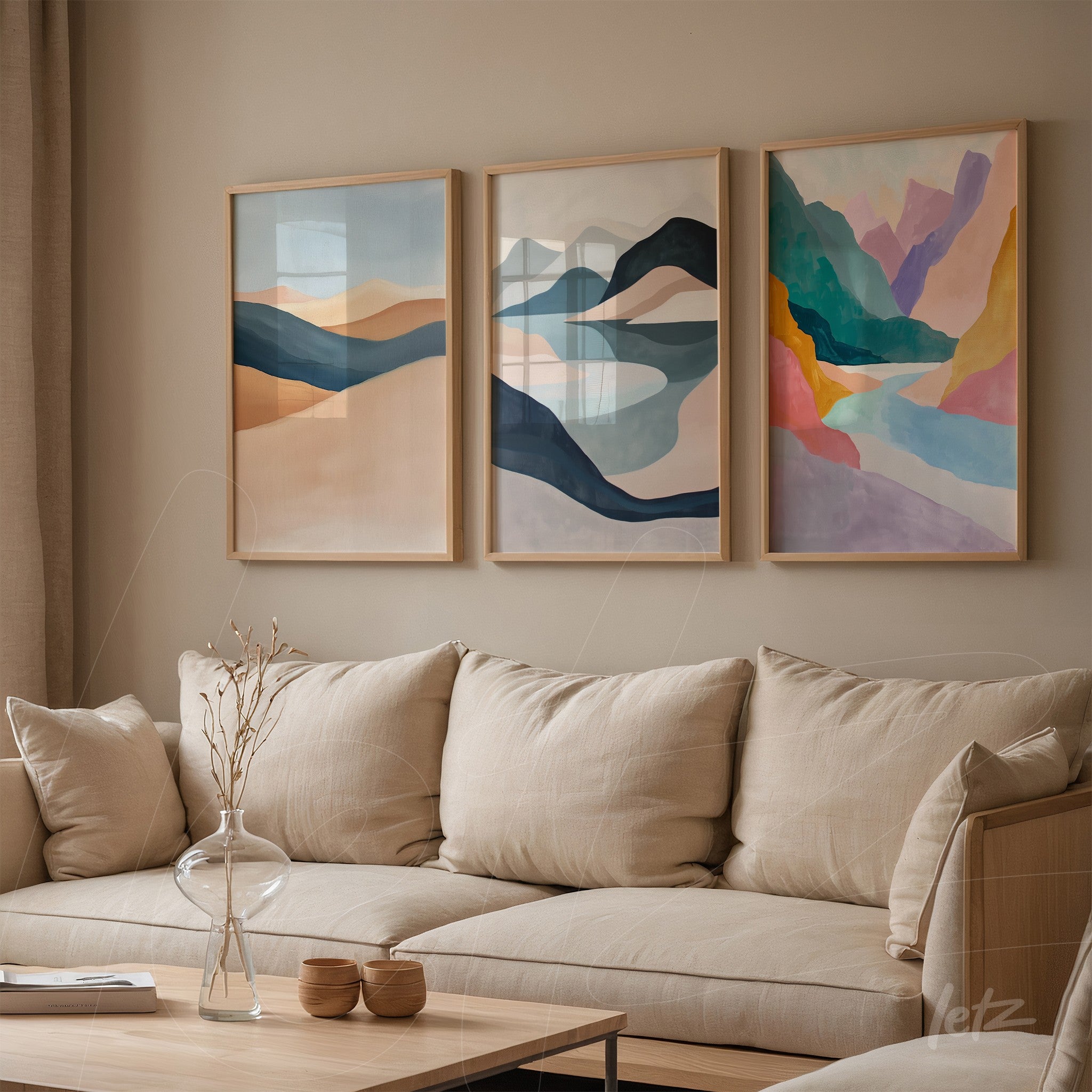 set of three abstract art pieces in light wood frames displayed on a neutral wall next to a beige sofa