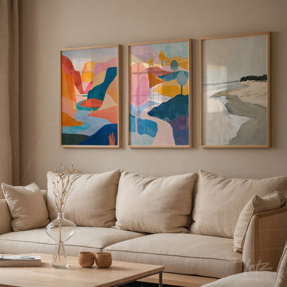 composition of three framed artworks featuring abstract landscapes in vibrant shades of blue, orange, and pink displayed on a neutral wall next to a light fabric sofa