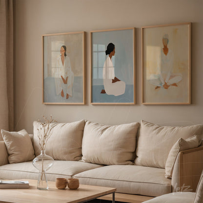 set of three framed artworks depicting women in a minimalist style with light wood frames displayed on a neutral wall next to a linen sofa
