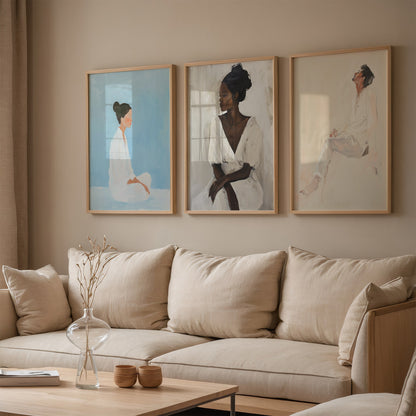 set of three artistic portraits in light wood frames on beige wall above a neutral sofa
