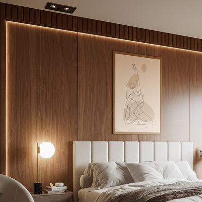 abstract line art of a female figure with light frame displayed above a bed in a modern bedroom