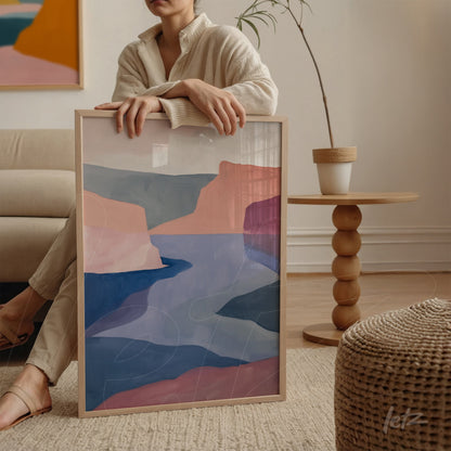 framed abstract wall art in shades of pink and blue displayed next to a person on a round table