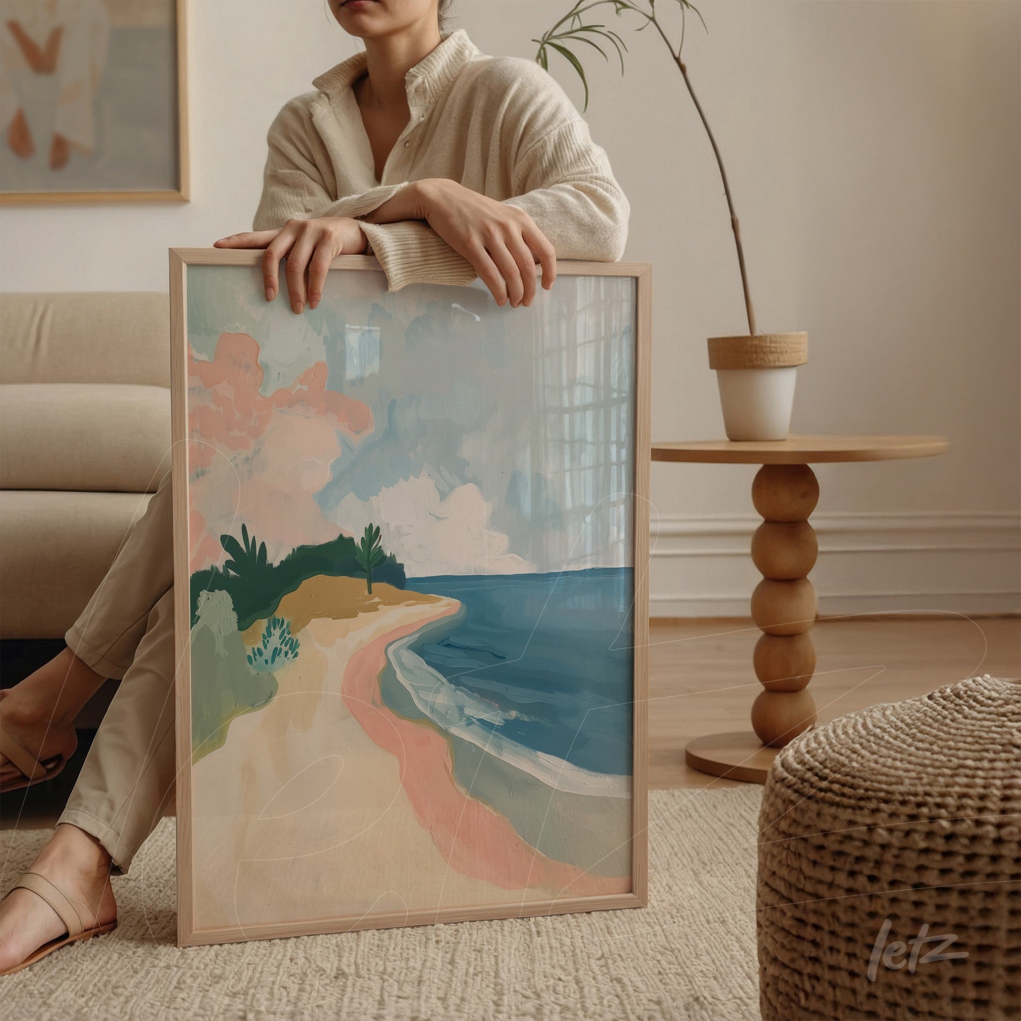framed artwork in light wood depicting an abstract beach scene with soft colors of sand, sea, and greenery