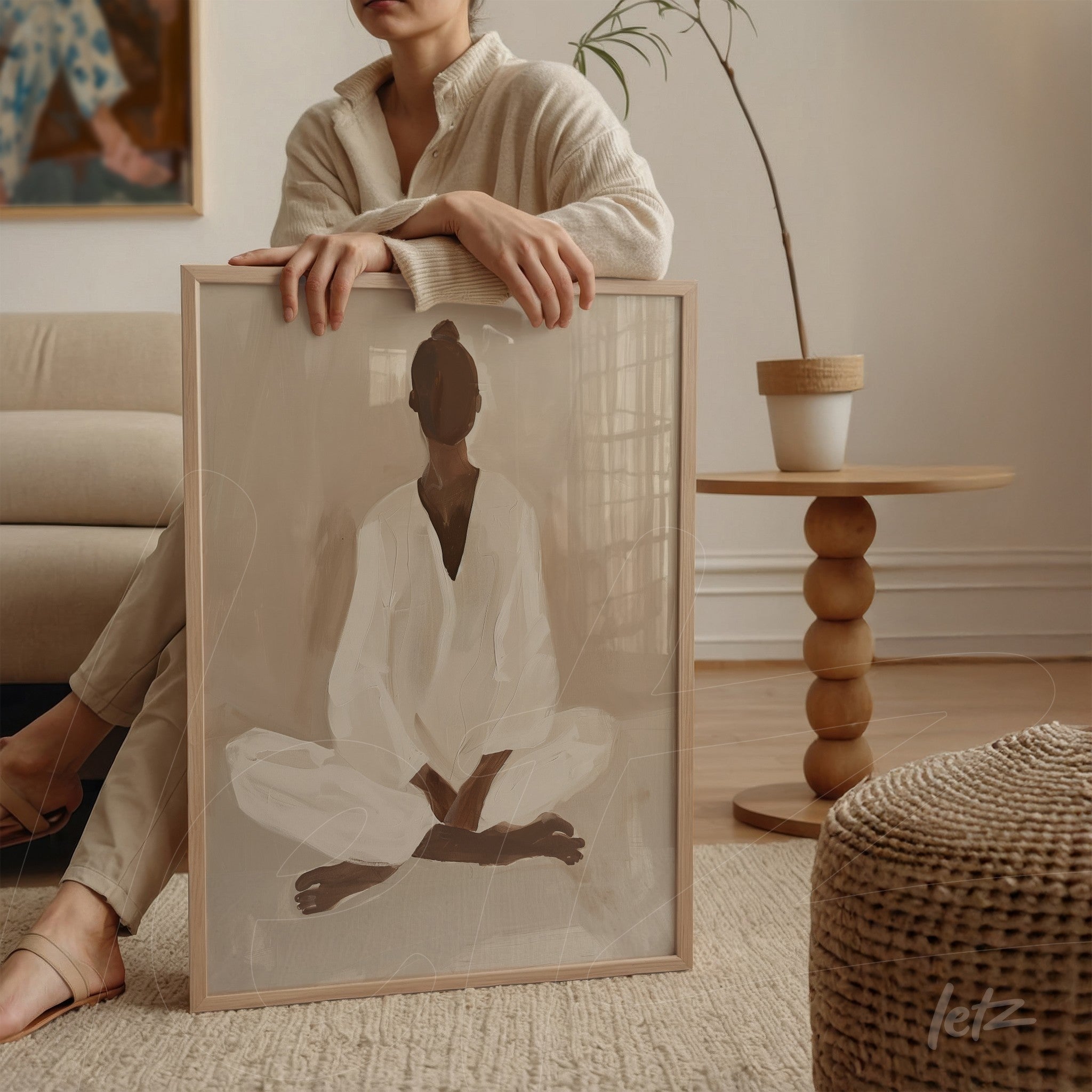 framed minimalist artwork of a meditating figure with light wood frame placed next to a sofa on a side table