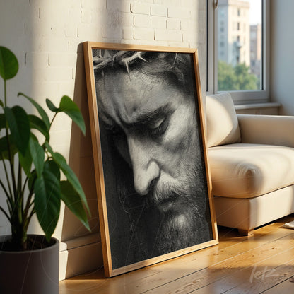 framed black and white portrait of Christ with a contemplative expression in a light wood frame leaning against a sofa