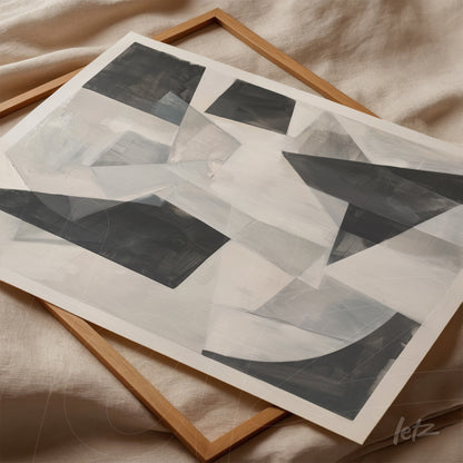 abstract artwork with geometric shapes in shades of gray and white, resting on light fabric in a wooden frame