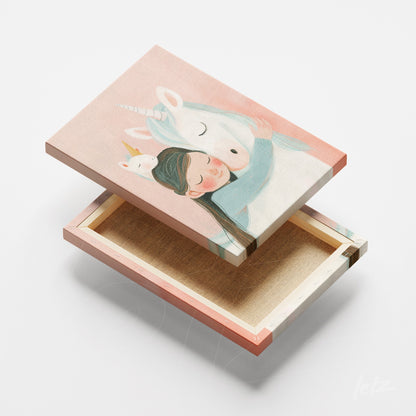 canvas print featuring illustration of a girl hugging a unicorn against a soft pink background