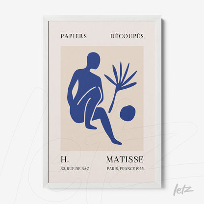 framed wall art featuring a human figure in blue, foliage, and a circle, with a white frame and light background