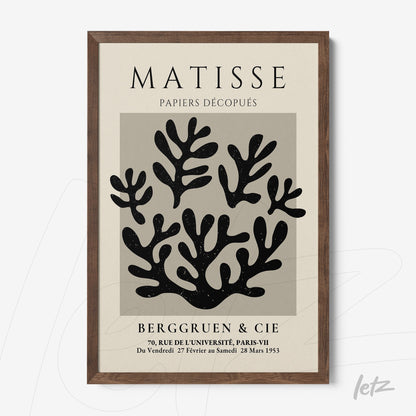 framed wall art featuring modern paper cutouts in shades of black with a dark wood frame and light gray background
