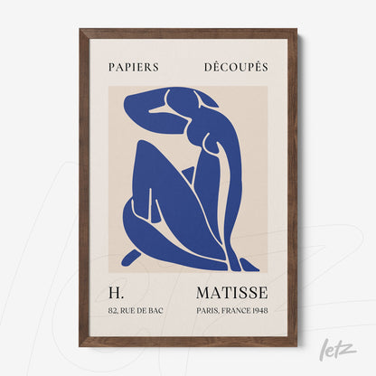 framed artwork featuring blue paper cutouts inspired by Matisse with a dark wood frame and light background