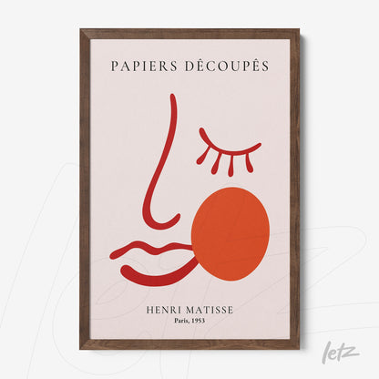 framed artwork depicting a modern face in red and pink tones with dark wood frame