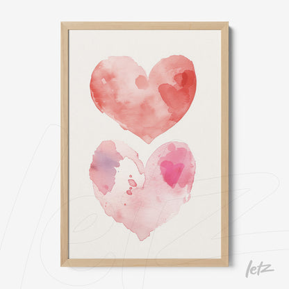 framed wall art featuring watercolor illustration of two hearts in shades of pink and red with light wood frame