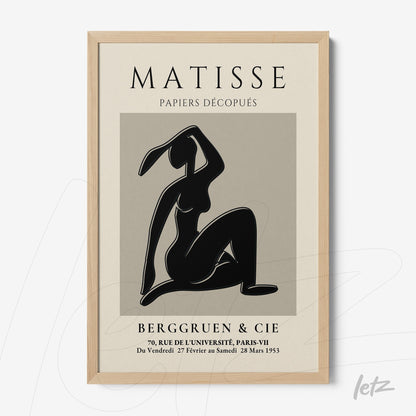 framed wall art featuring a stylized female figure in black on a gray background with light wood frame