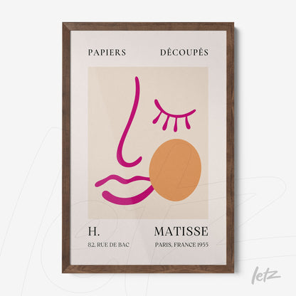 framed modern wall art featuring a stylized face in pink and orange tones with a dark wood frame against a cream background