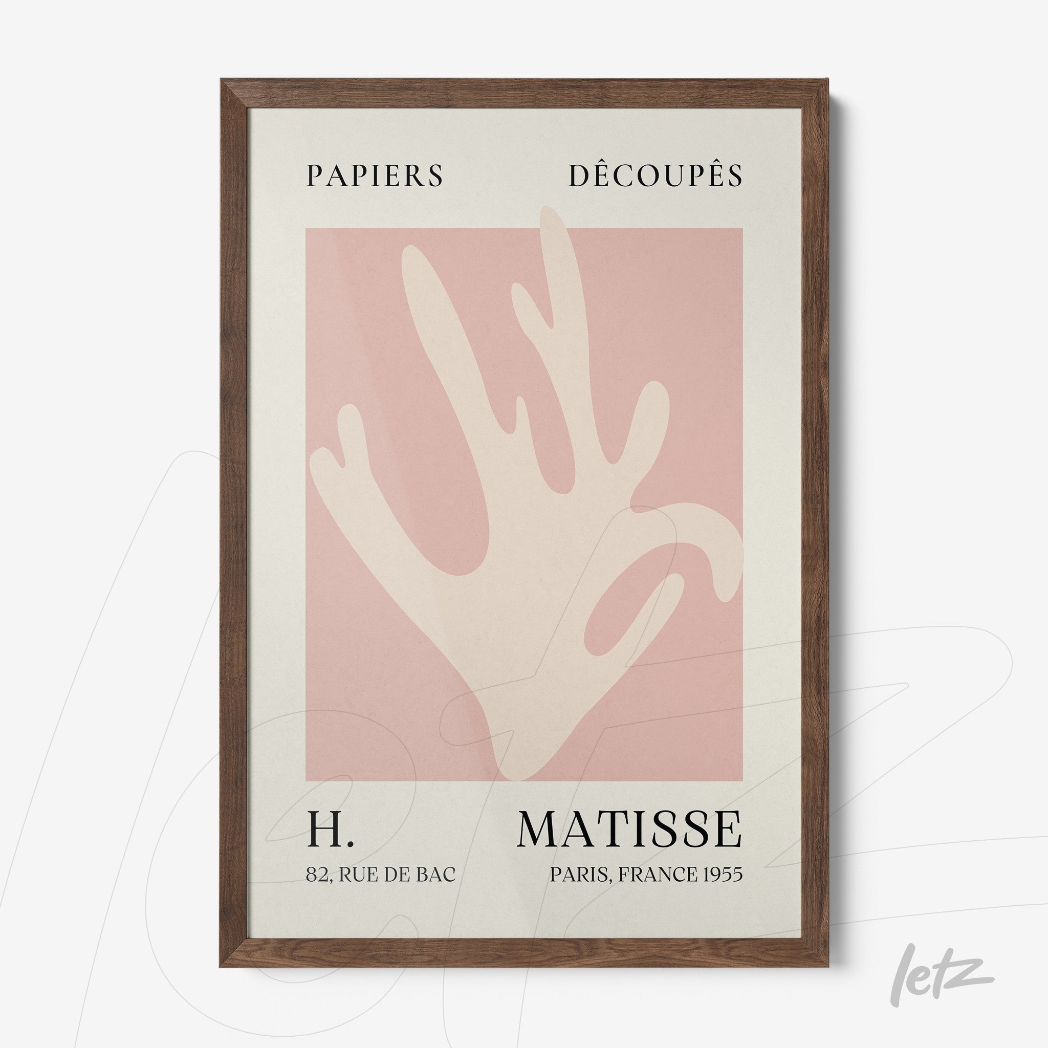 framed wall art featuring modern paper cutouts on a pink background with dark wood frame
