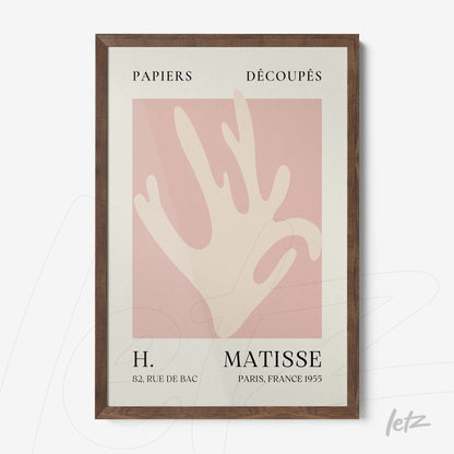 framed wall art featuring modern paper cutouts on a pink background with dark wood frame