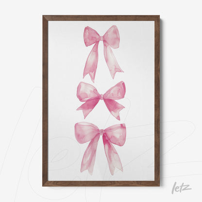 framed artwork featuring three pink watercolor bows in a dark wood frame
