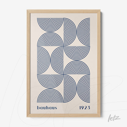 poster featuring a geometric design with blue concentric circles and 'bauhaus 1923' text, framed in light wood